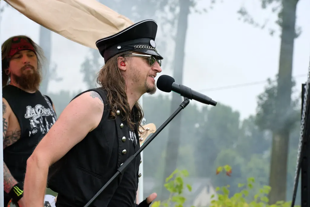 Zanger met pet en zonnebril op het podium in de boomgaard